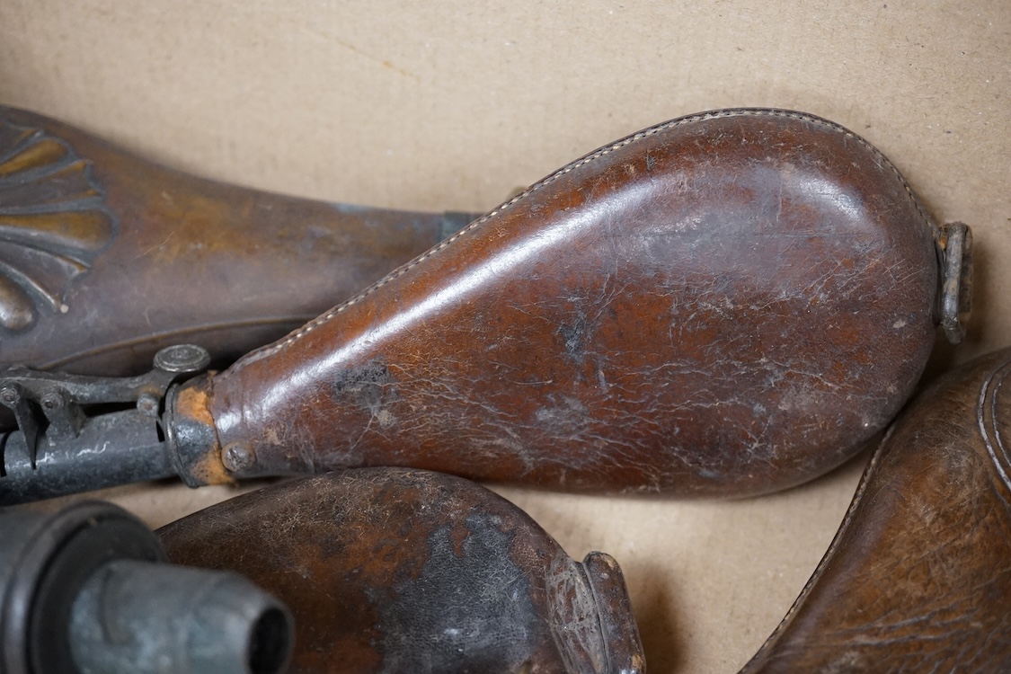 Three gun-sized copper powder flasks, two of which are embossed, together with four leather shot bags each with sprung chargers, two iron and two brass examples, one of which is embossed with a hunting scene (7)